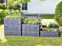 Mehrere Hochbeete aus Holz sind mit lebendigen Blumen und Pflanzen in einem sonnigen Garten gefüllt.