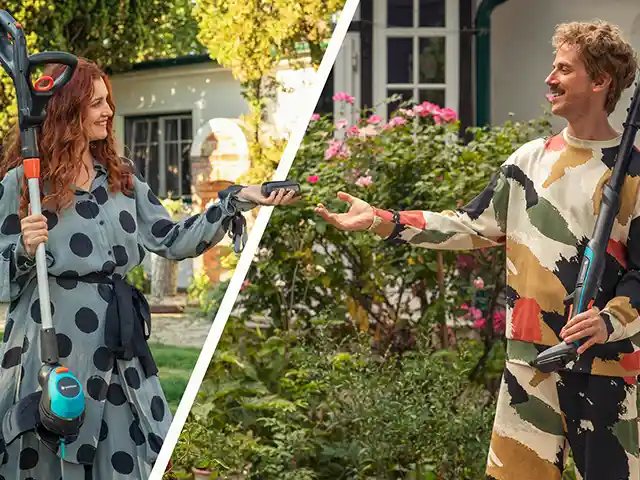 Mann und Frau im Garten nutzen Gartengeräte und übergeben einen Akku