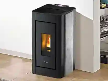 Ein schwarzer Heizofen brennt in einer modernen Wohnungsecke auf hellem Holzboden.