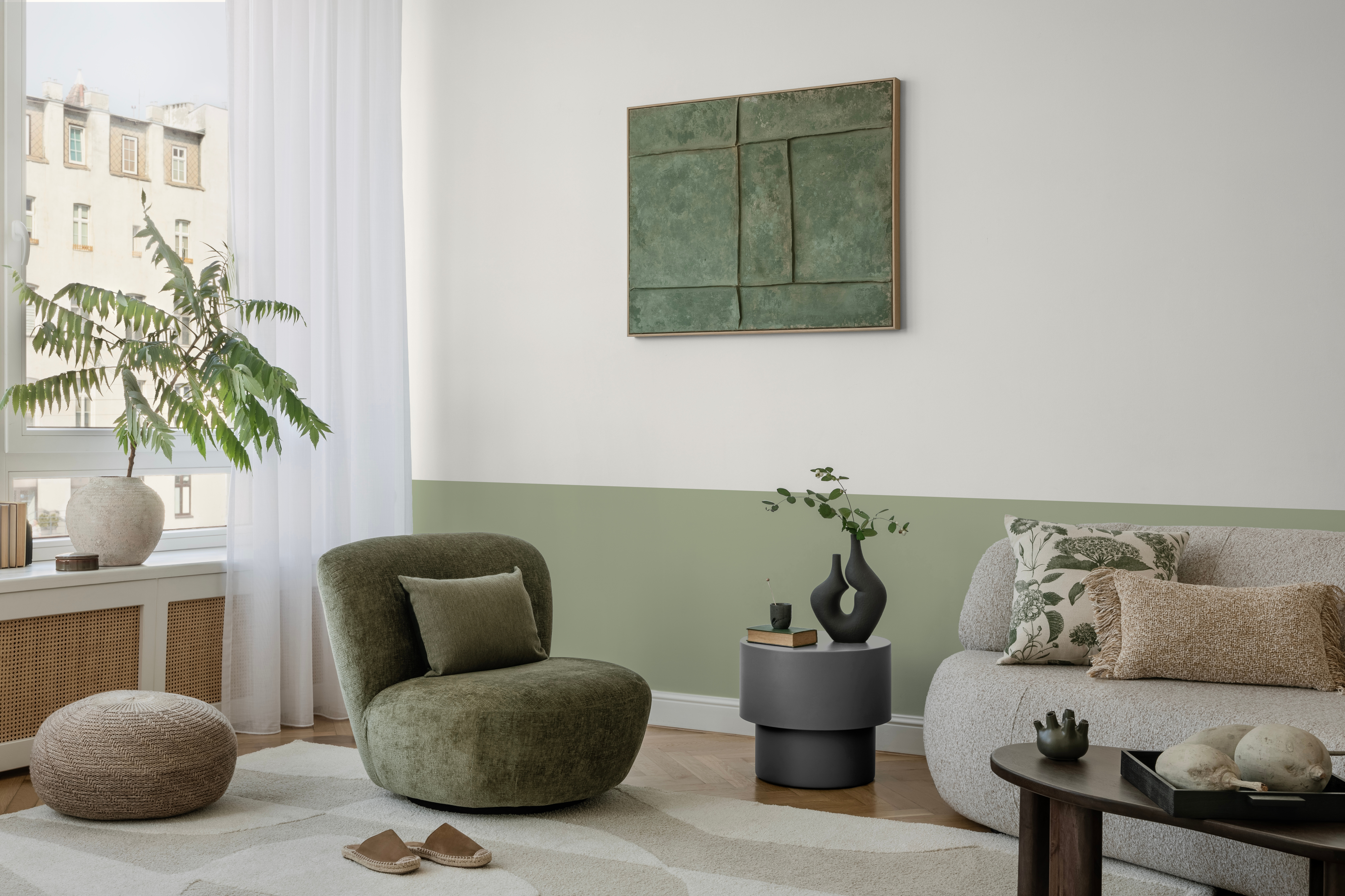 Pastelgrüne Wand mit grünen und grauen Sesseln. 