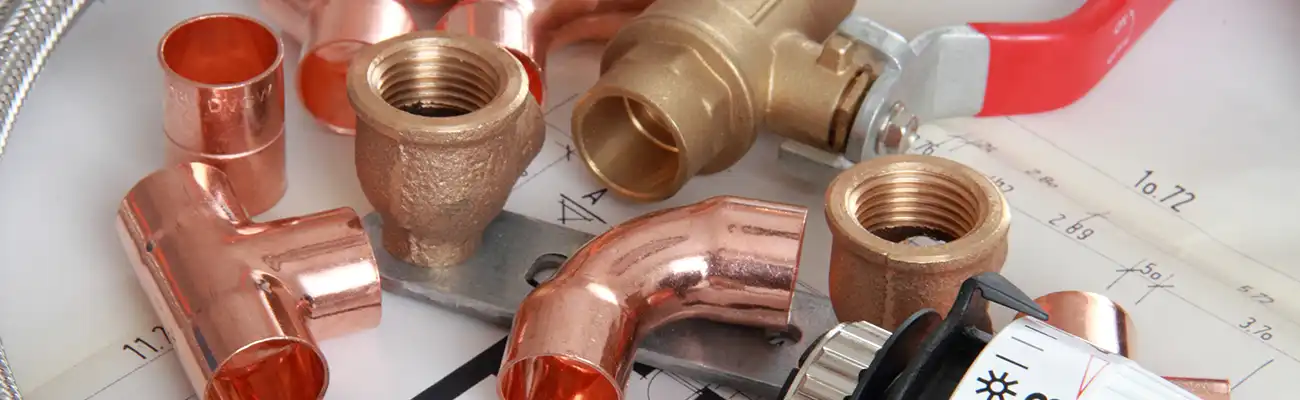 Kupferrohre und Fittinge liegen auf einer technischen Zeichnung.