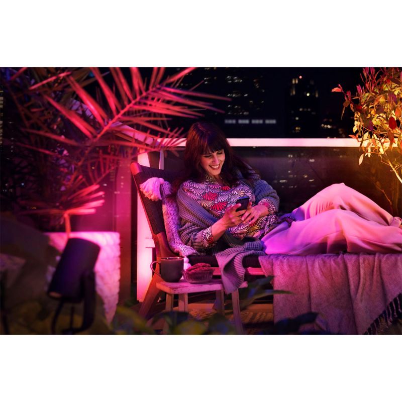 Eine Frau die auf Ihrem Garten ofa liegt und im Hintergrund das Licht der Philips Hue leuchtet