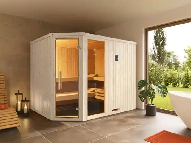 Eine Holz-Sauna steht in einem hellen Raum mit großem Fenster.