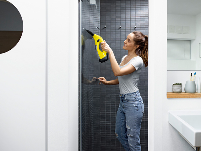 Frau mit Kärcher Fenstersauger in der Dusche