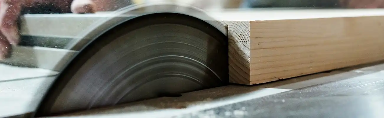 Ein Kreissägeblatt schneidet Holz in einer Werkstattumgebung präzise durch.