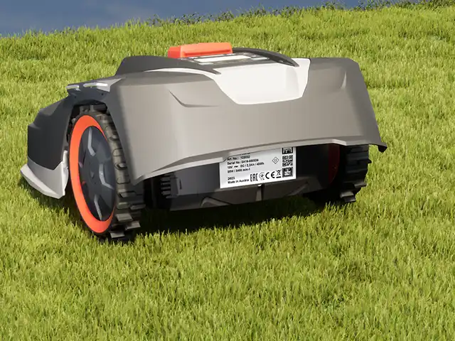 Ein automatischer Rasenmäher fährt über eine grüne Wiese unter einem blauen Himmel.