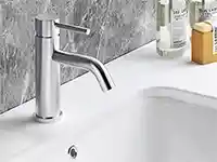 Ein moderner Wasserhahn über einem weißen Waschbecken, flankiert von Toilettenartikeln auf einer Marmorwand.