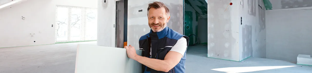 Freundlicher Handwerker hält Holzplatte in der Hand